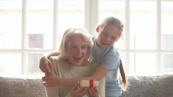 Barnbarn gör överraskning kramas lycklig gammal mormor presentera födelsedagspresent — Stockvideo