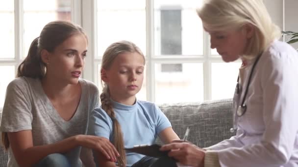 Заботливая женщина врач педиатр говорить с ребенком девочка делать заметки — стоковое видео