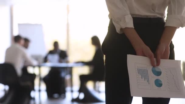 Женщина-менеджер держит бумажный отчет финансовой статистики за спиной — стоковое видео