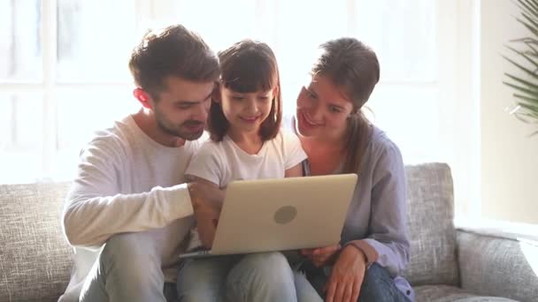 Child daughter laughing looking at laptop watching cartoons with parents — Stock Video