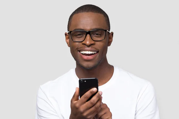 Headshot retrato sorrindo homem africano segurando smartphone olhando para a câmera — Fotografia de Stock