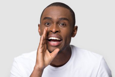 Afrikalı adam kameraya bakarak fısıldayarak ağzına yakın el ele tutuşuyor