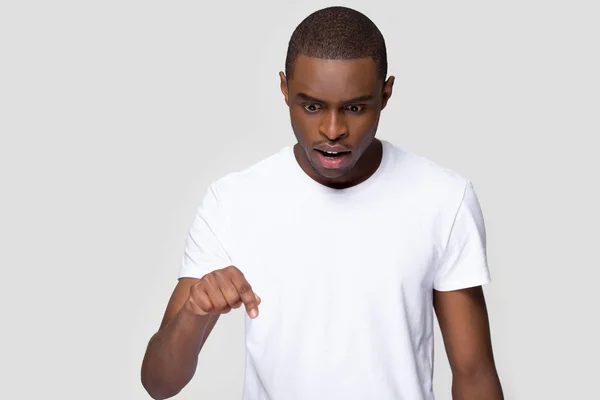 Chockad afrikansk man ser pekar ner pose på grå blank — Stockfoto