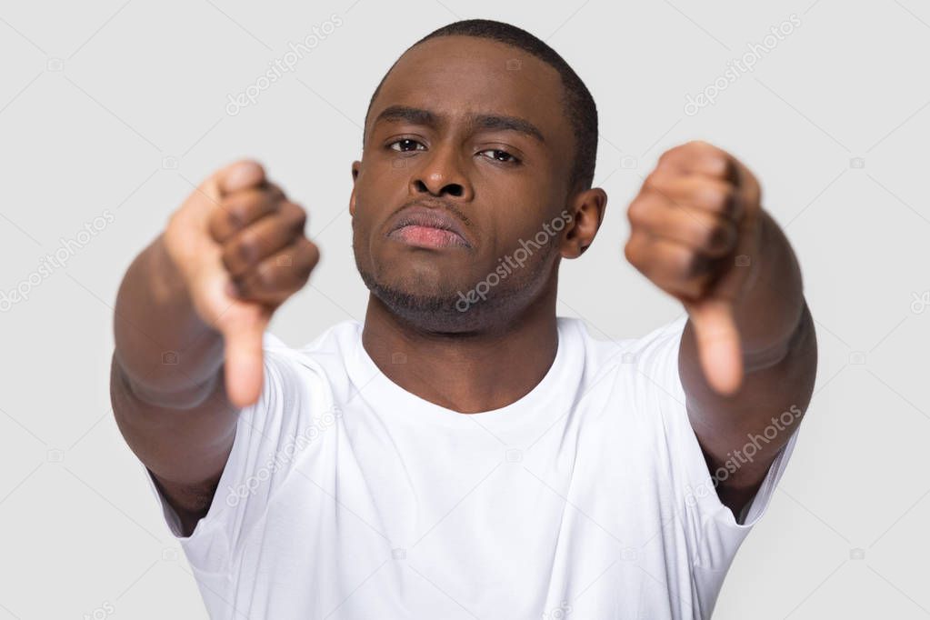 Serious african man showing thumbs down gesture of disapproval