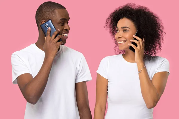 Atractiva pareja africana sosteniendo teléfonos mirándose — Foto de Stock