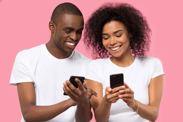 Ελκυστικό αφρικανικό ζευγάρι κρατώντας έξυπνα τηλέφωνα χαμογελώντας έχοντας τη διασκέδαση — Φωτογραφία Αρχείου