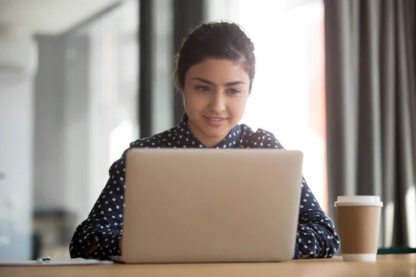 Skoncentrowany indyjski kobieta pracownik zajęty praca w laptop w biuro — Zdjęcie stockowe