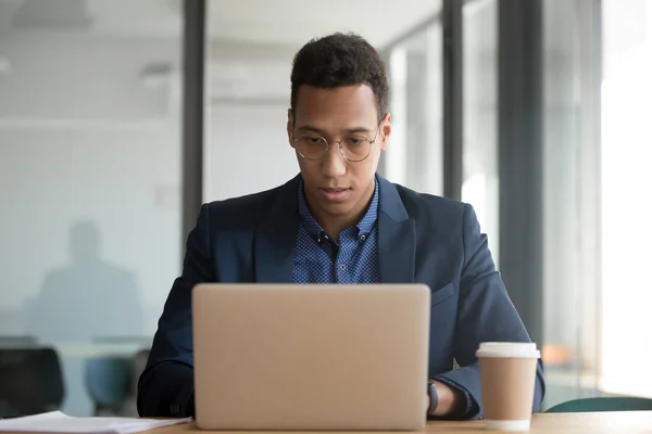 Concentrated african American businessman working at laptop in office — Stock Photo, Image