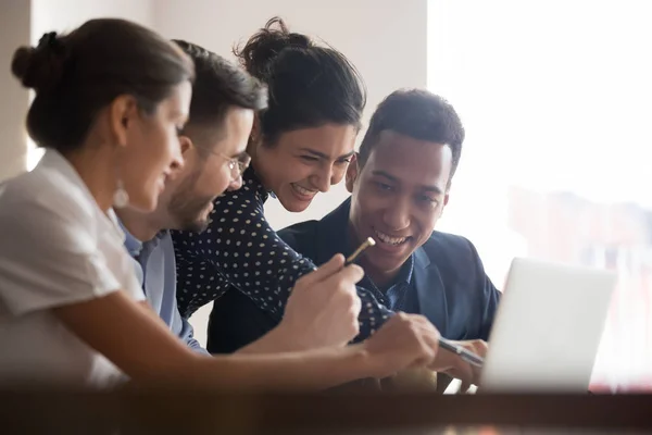 Diversos colegas sonrientes se ríen de lluvia de ideas usando computadora portátil — Foto de Stock