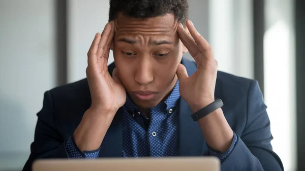 Tired african American employee suffering from headache using laptop — Stock Photo, Image