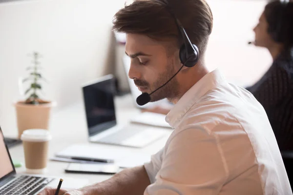 Serieuze mannelijke werknemer in headset make Notes Consulting client online — Stockfoto