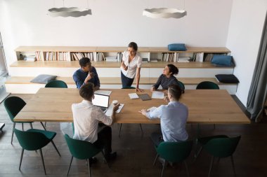 Çok ırklı çalışanlar kadın takım lideriyle fikirleri tartışıyor