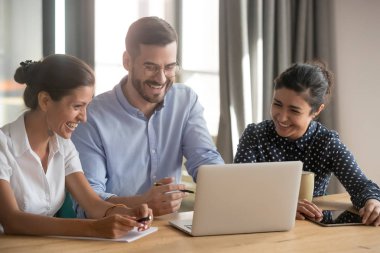 Gülümseyen farklı çalışanlar dizüstü bilgisayarda komik video izlemek