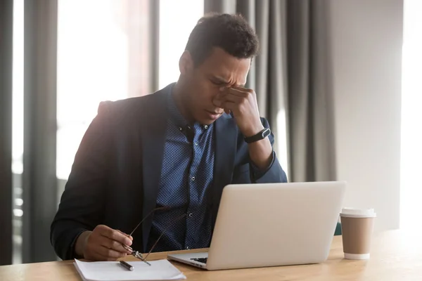 Cansado hombre de negocios negro quitarse gafas que sufren de dolor de cabeza — Foto de Stock