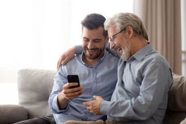 Mutlu kıdemli baba ve bin yıllık oğlu birlikte akıllı telefon kullanarak