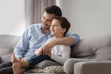 Gülümseyen baba ve oğul evde kanepeye sarılmak