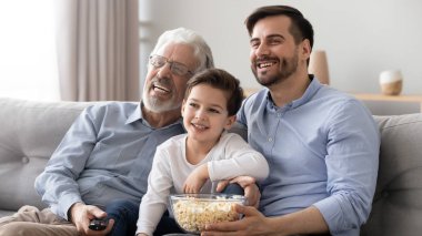 Gülümseyen baba, oğul ve dedesi evde Tv izlemek