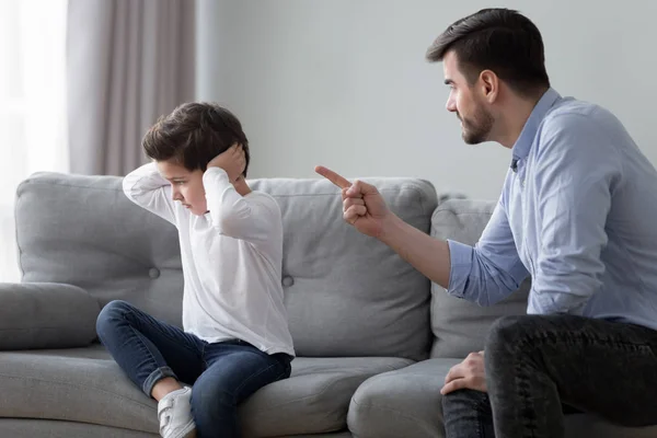 Сердитий тато записує дошкільника сина, який має суперечку вдома — стокове фото