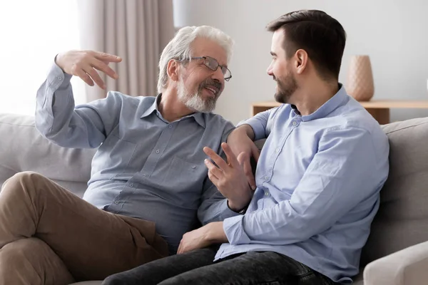 Happy senior father talk relaxing on couch with millennial son — Stock Photo, Image