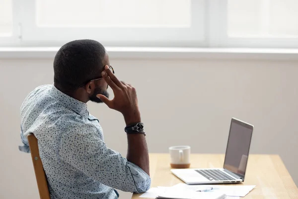 Tankeväckande afroamerikansk affärsman tittar ut fönster sitter på kontoret — Stockfoto