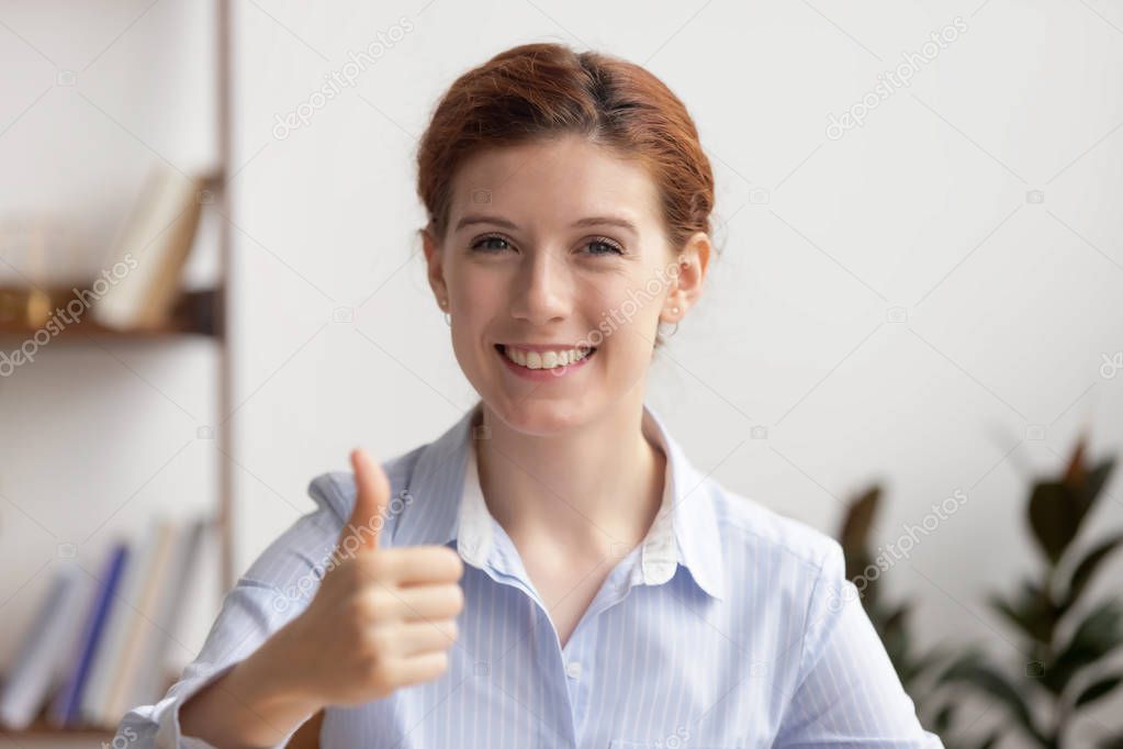Portrait happy smiling businesswoman showing thumbs up at workplace
