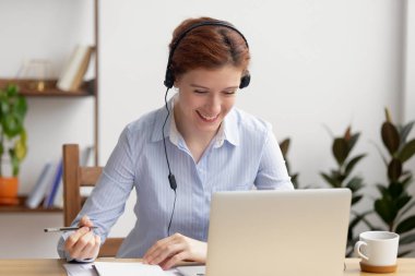 Ofis masasında kulaklık kendi kendine çalışma Mutlu gülümseyen iş kadını