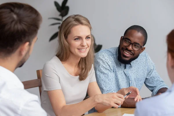 Happy smiling young woman talking with coworkers at work — Stock Photo, Image