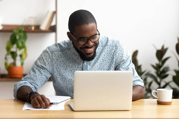 Head shot smiling african-american manager using laptop looking at screen — Stock Photo, Image