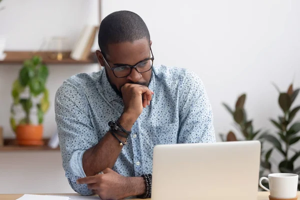Tiro alla testa seriamente perplesso uomo d'affari afroamericano guardando il computer portatile — Foto Stock