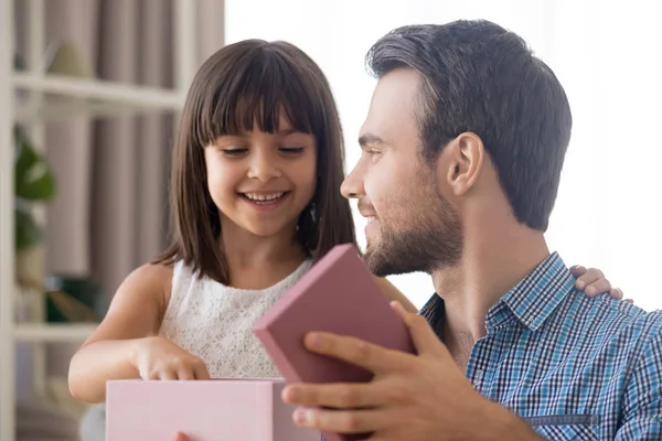 Feliz padre joven y pequeña hija abren regalo juntos — Foto de Stock