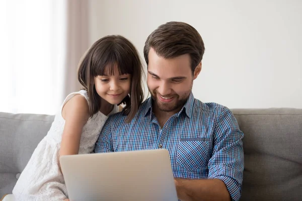 Улыбающийся папа наслаждается просмотром видео на ноутбуке с дочерью — стоковое фото