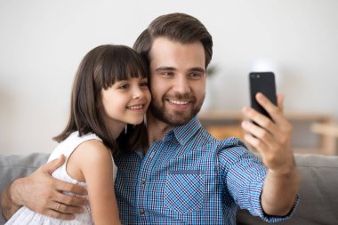 Gülümseyen genç baba ve küçük kızı akıllı telefonda selfie yapıyor