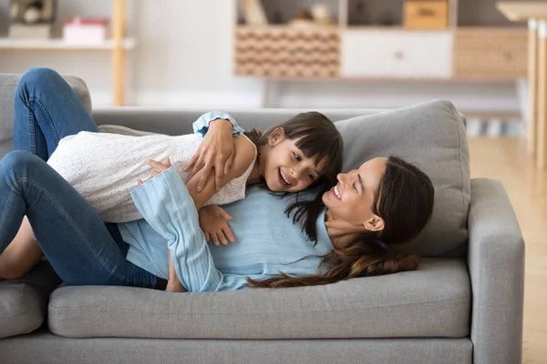 Mãe feliz e pequena filha relaxar se divertindo no sofá — Fotografia de Stock