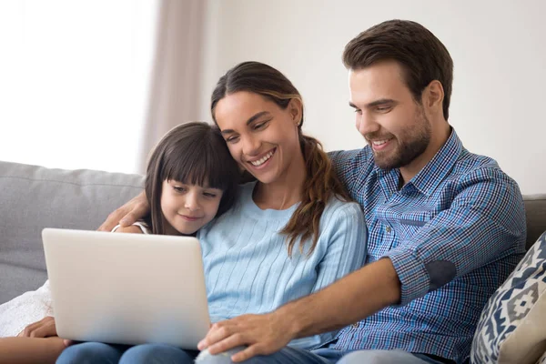 Счастливые молодые родители с маленькой дочкой смотрят мультики на ноутбуке — стоковое фото