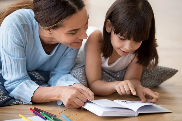 Cuidar mamá leyendo interesante libro con hija pequeña —  Fotos de Stock