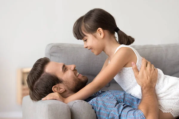 Ragazza carina rilassarsi con il giovane papà sdraiato sul divano — Foto Stock