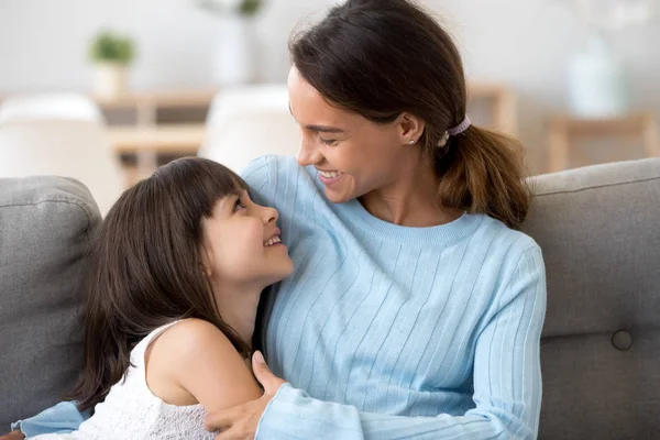 Anak perempuan dan ibu muda berpelukan santai di sofa — Stok Foto