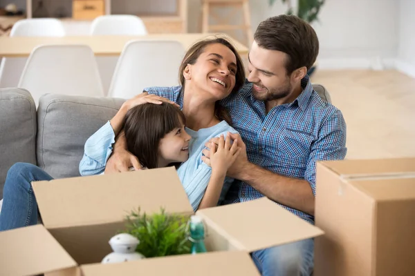 Sonrientes padres relajarse con su hija en el sofá de casa — Foto de Stock