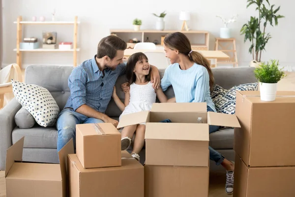 Aufgeregte Eltern entspannen sich am Umzugstag mit Tochter auf dem Sofa — Stockfoto