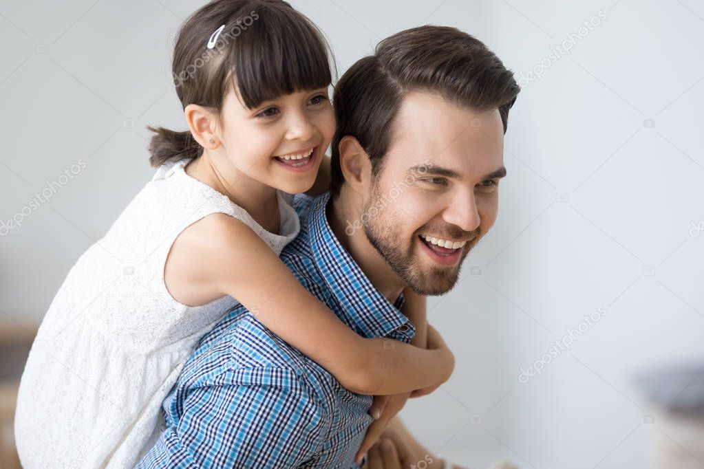 Happy girl piggyback young dad playing together