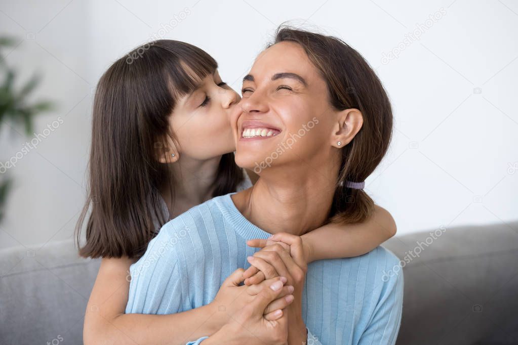 Cute little daughter kiss happy mom on cheek