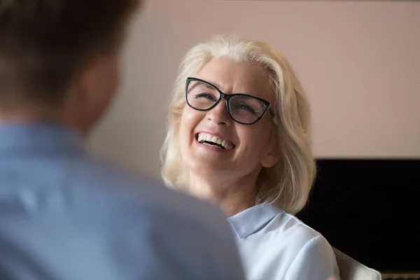 Привлекательная взрослая деловая женщина смеялась над шуткой коллеги во время перерыва — стоковое фото