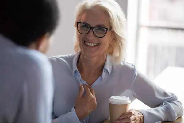 Opgewonden volwassen zakenvrouw praten met collega tijdens koffiepauze — Stockfoto