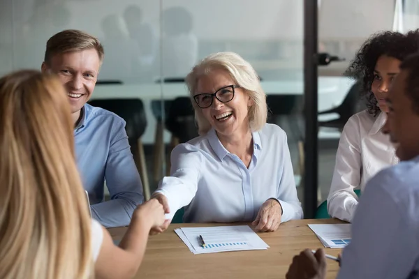 Mature businesswoman shaking hand of business partner at meeting — Stock Photo, Image