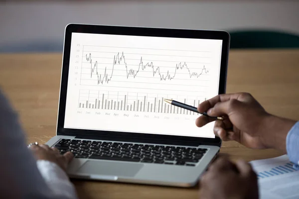 Primer plano empresario afroamericano analizando gráficos en la pantalla del ordenador portátil —  Fotos de Stock