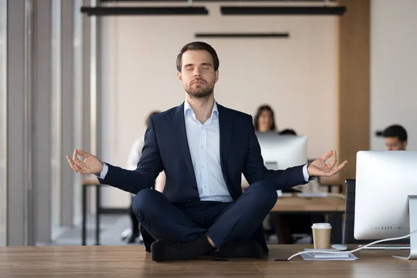 Мирный бизнесмен медитирует с закрытыми глазами на рабочем месте — стоковое фото