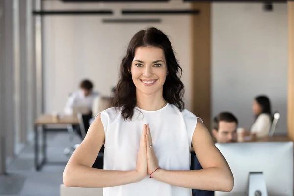 Portret van lachende vrouwelijke werknemer mediteren in gebed pose — Stockfoto