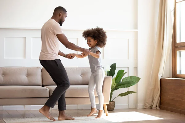 Happy african father and kid daughter jump dance at home — Stok fotoğraf