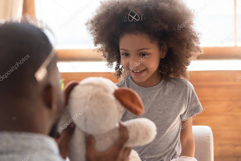 Cute african kid daughter princess wearing crown playing with dad