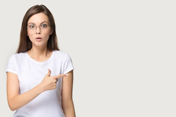 Millennial surprised woman in glasses pointing finger at copy space — Stock Photo, Image